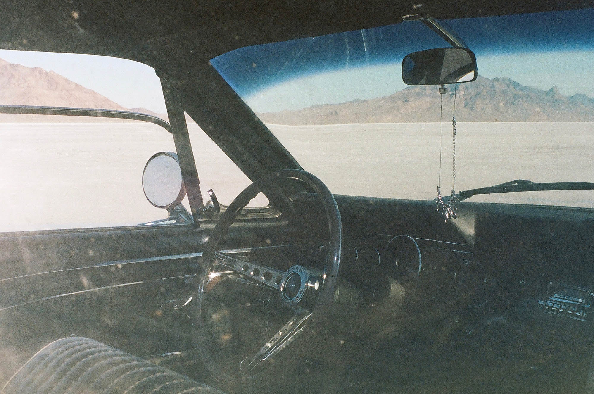 The interior of a vintage Ford Mustang with the salt flats in the distance